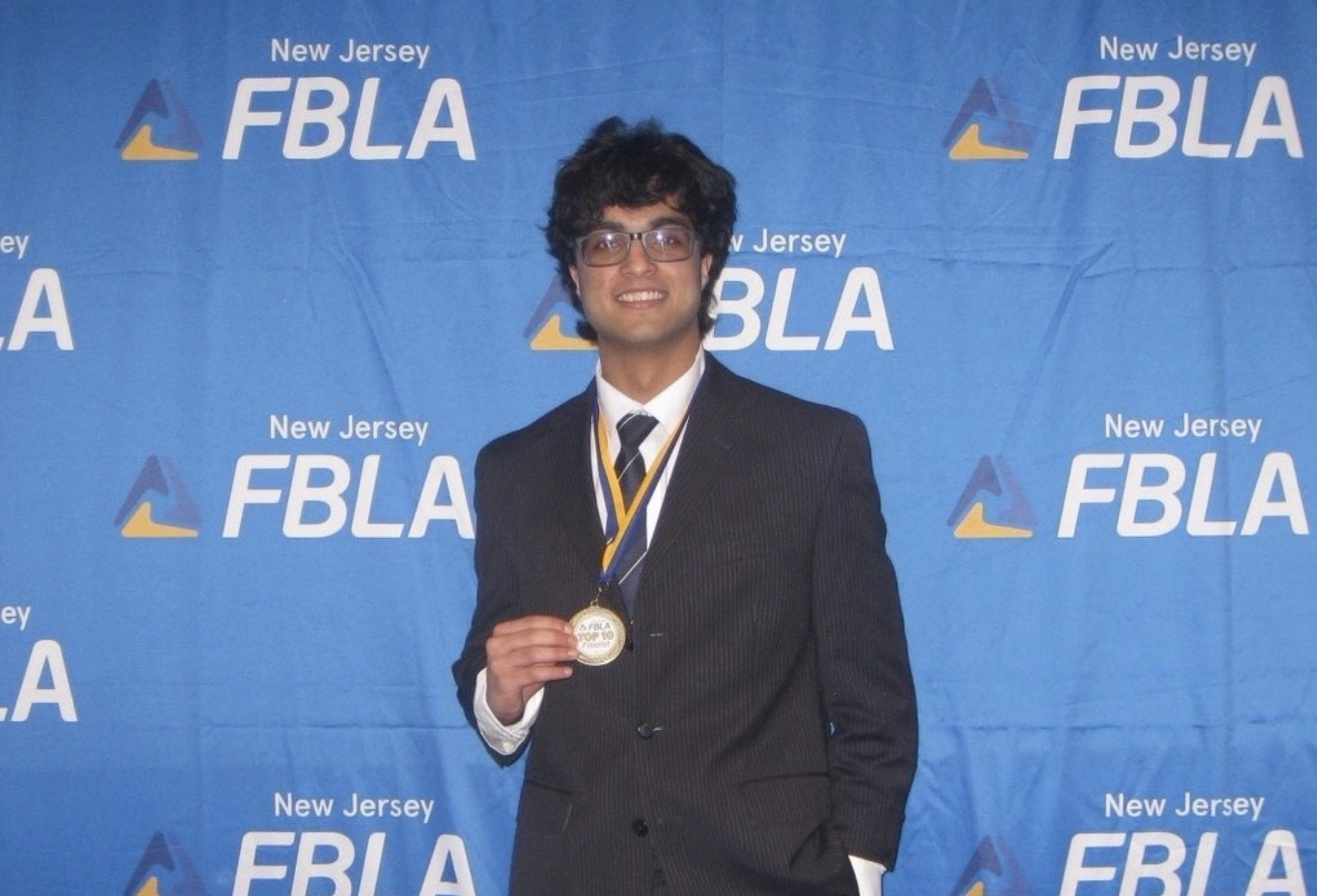 Rohan Mruthik in a suit against a blue FBLA background